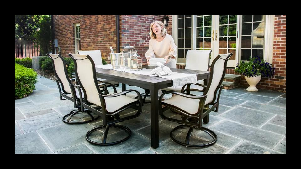 blond woman setting table part of yardbird pepin outdoor dining set on patio outside