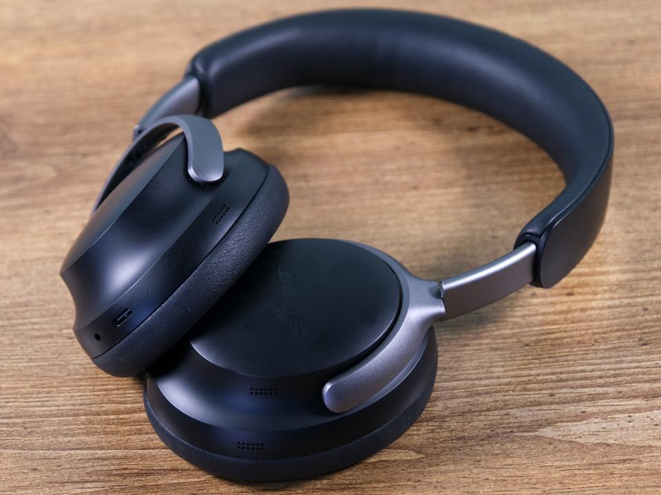 Black Bose QuietComfort Ultra headphones on a wooden table.