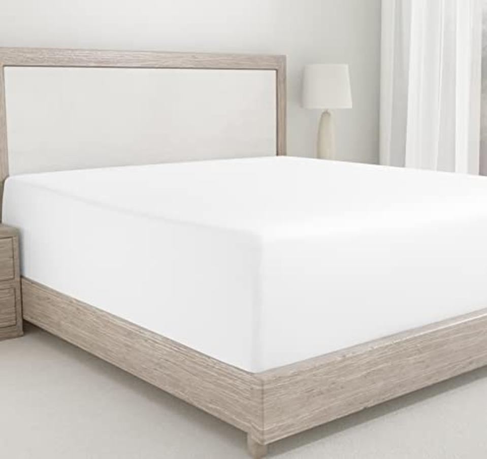 California Design Den fitted sheet in white on mattress and wooden bed frame.