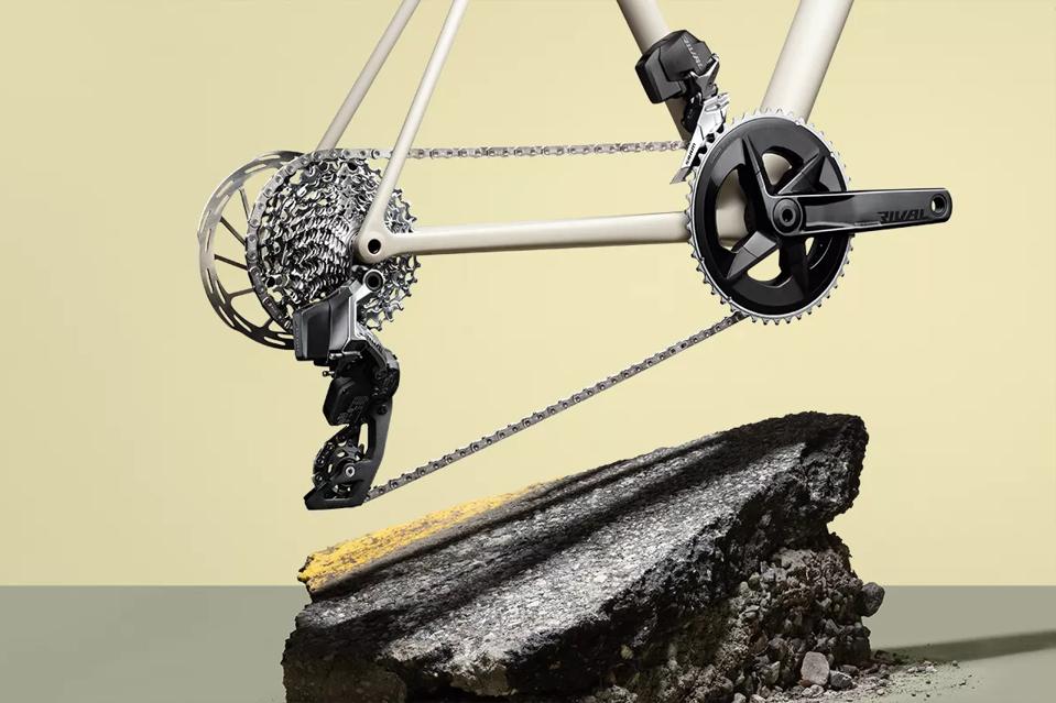 The Shimano Rival Etap AXS groupset on a tan background hovering above a rock