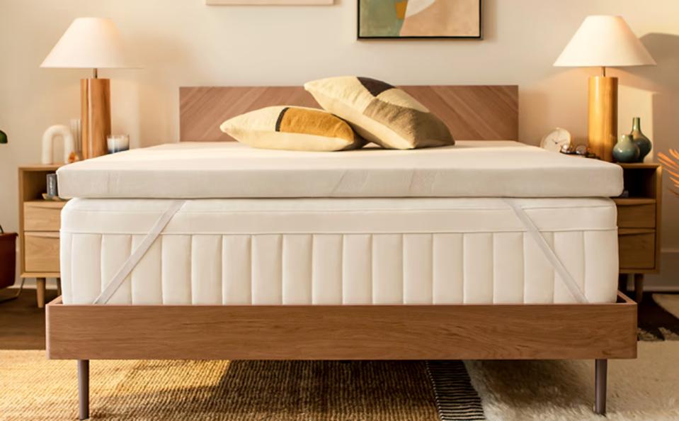 A Tempur-Pedic Adapt Topper on top of a mattress with a wooden bed frame underneath. 