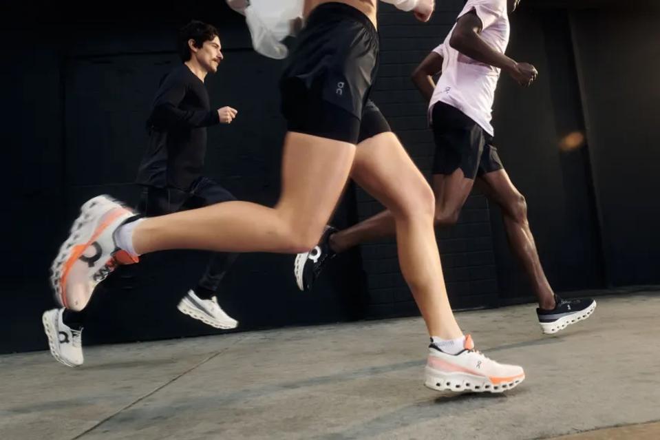 Three people running on a sidewalk wearing the On Cloudmonster 2 running shoe