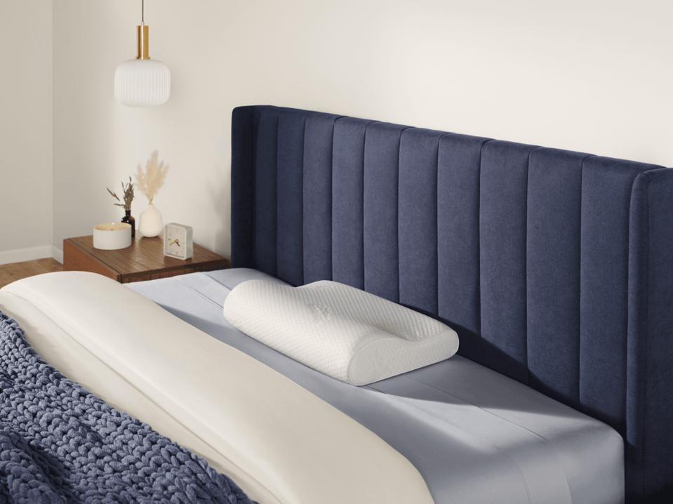 The Tempur-Pedic Neck Pillow on a bed.