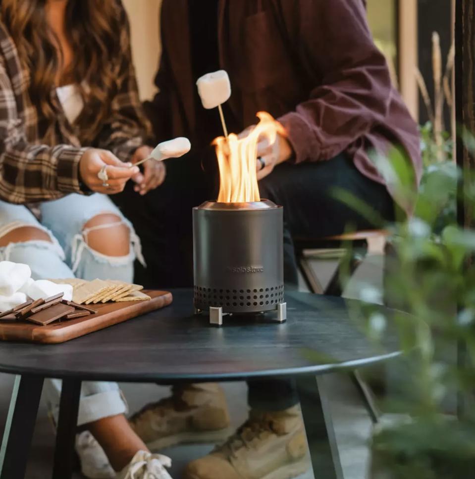 Small tabletop fire pit with two people roasting marshmallows