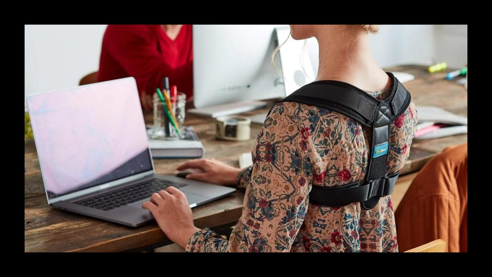 A woman wearing a posture corrector while sitting at a desk