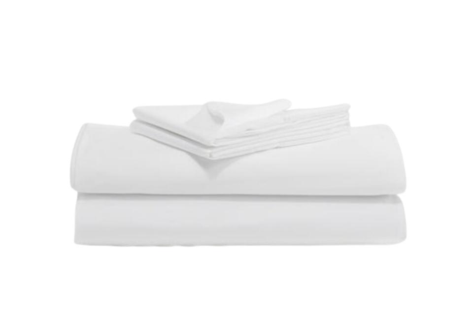 A neatly folded set of clean, white sheets and pillowcases against a white background. 