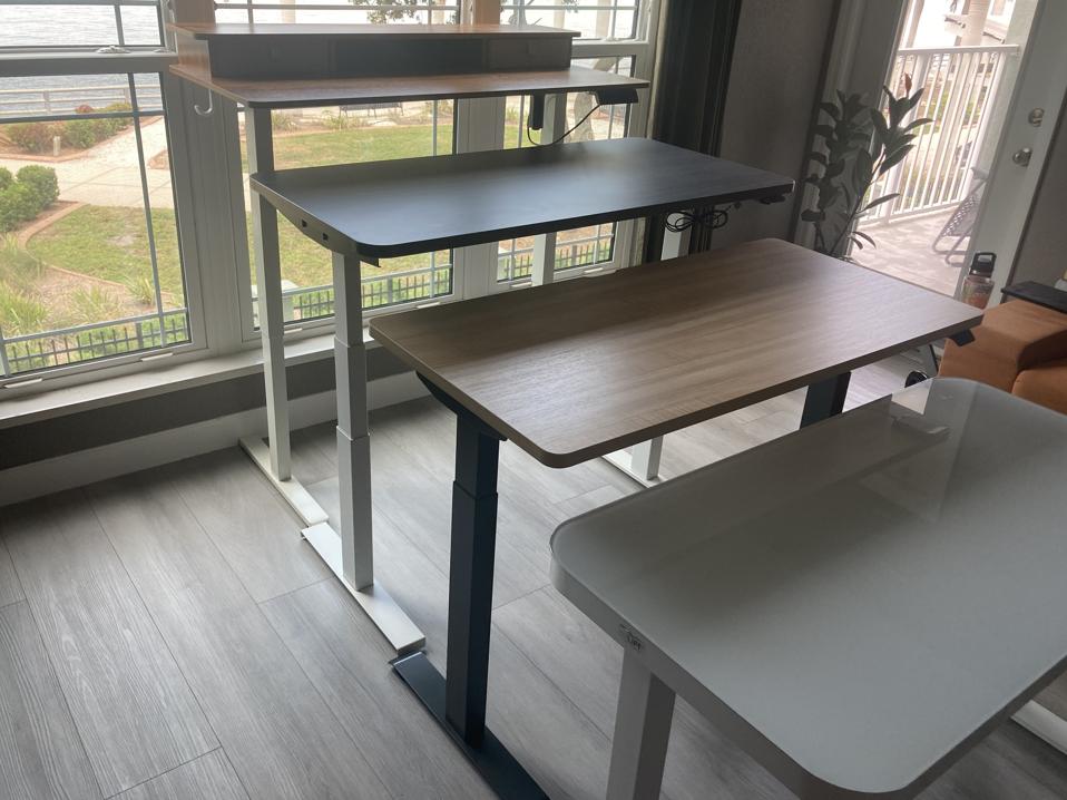 Four of the best standing desks in a row at different heights in front of a window 