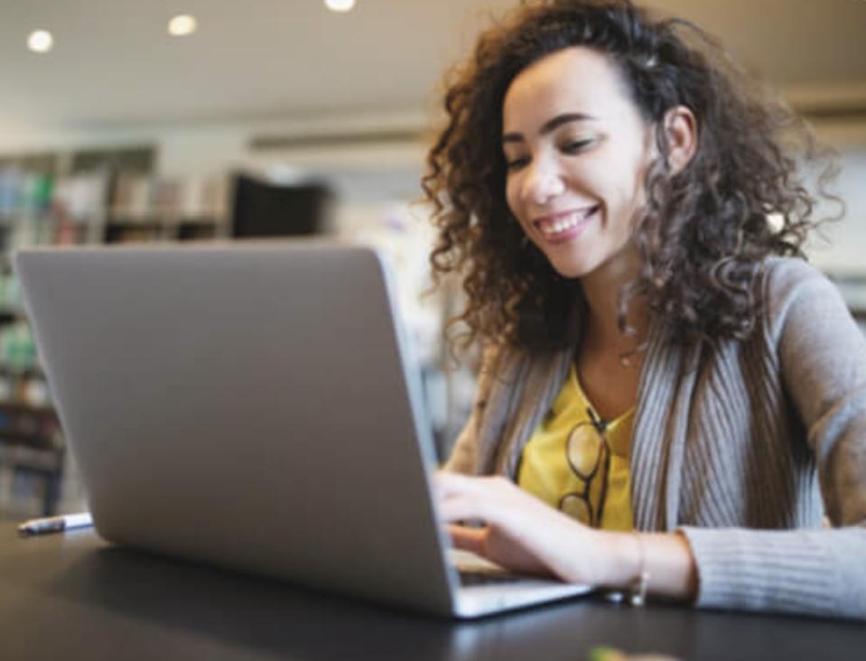 A woman smiling while on her laptop.