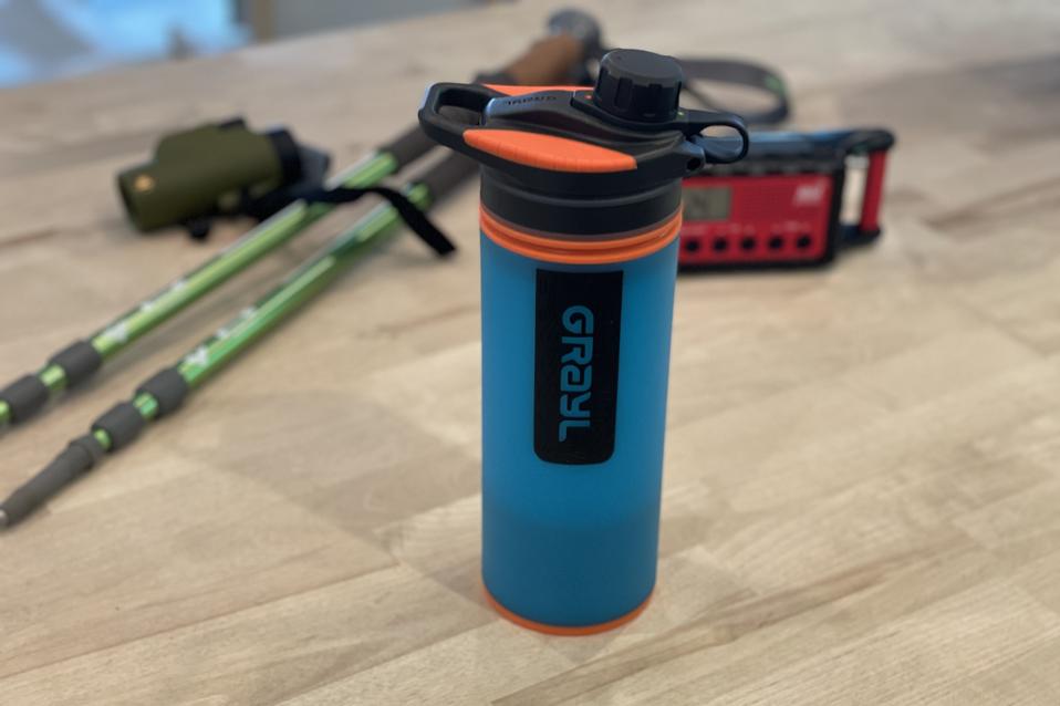 Grayl GeoPress water bottle in blue on a wooden table