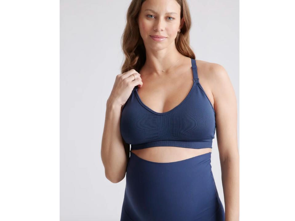 pregnant woman wearing dark blue quince low-impact seamless bra against off-white background