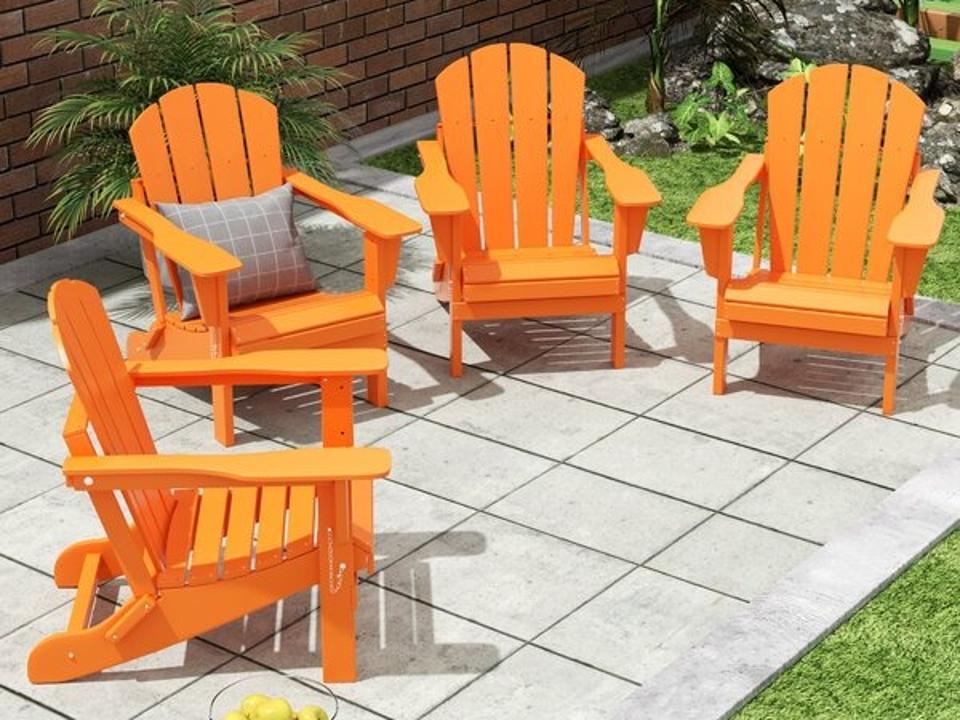 Four orange Loon Peak Folding Adirondack Chairs on an outdoor patio.