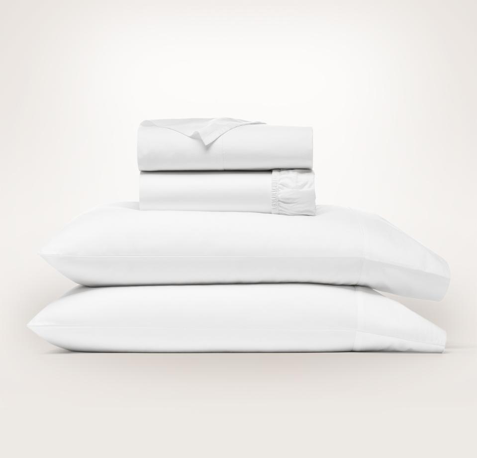 Boll & Branch sheets folded and stacked on two pillows against a cream background.