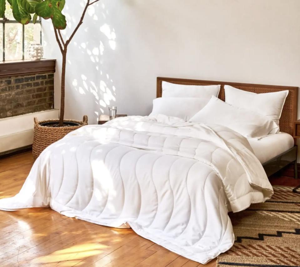 The Buffy Breeze comforter on a wood bed frame in a white bedroom. 