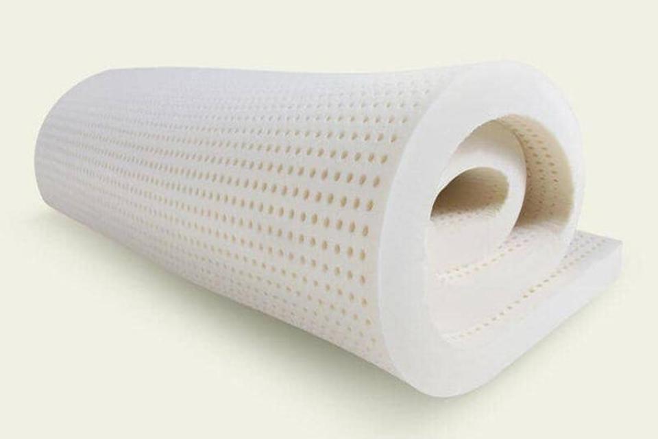 A latex mattress topper with rows of perforations against a white background. 