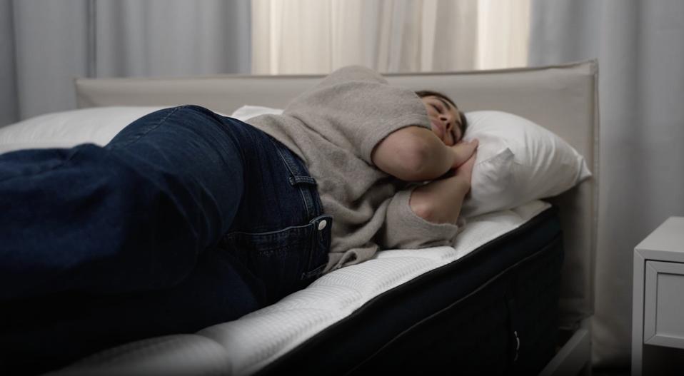 A person side sleeping on the Dreamcloud premier rest mattress.