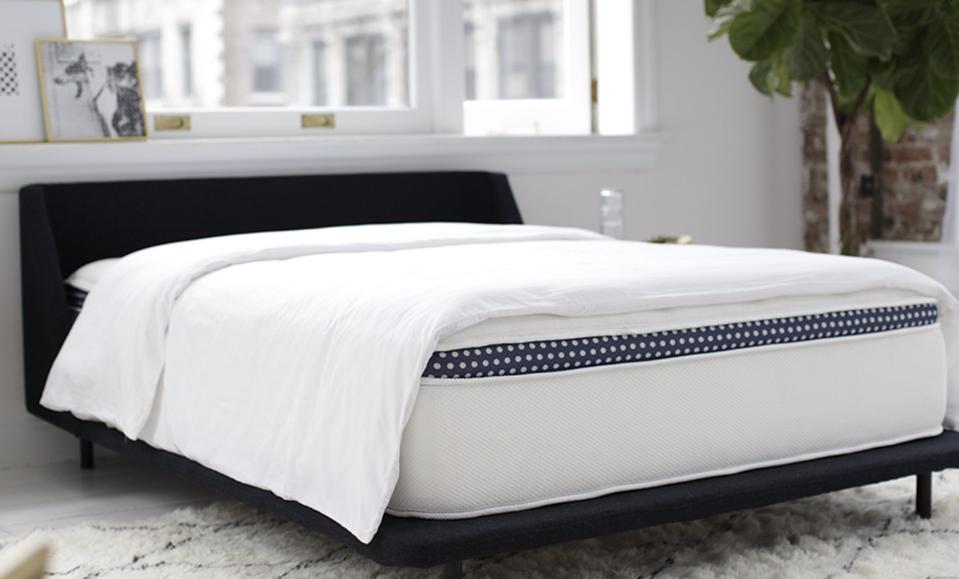 WinkBeds Luxury Hybrid Mattress on top of a shaggy carpet with a white comforter on top. 