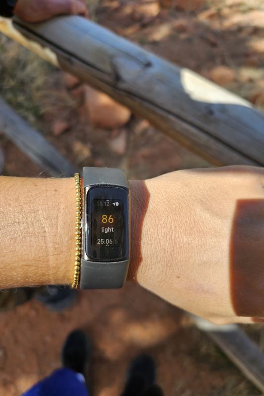 Fitbit Charge 6 showing heart rate with a trail in the background