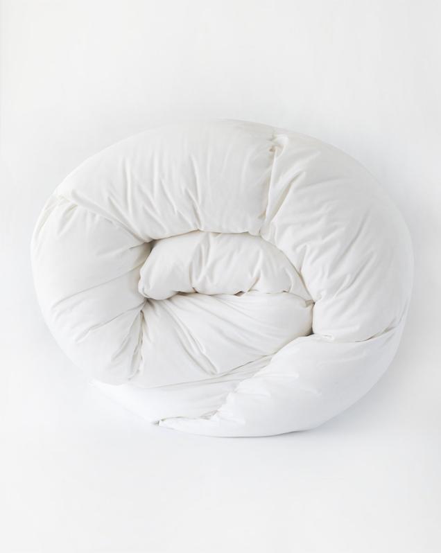 The Quince Down-Alternative Comforter rolled up on a white background. 