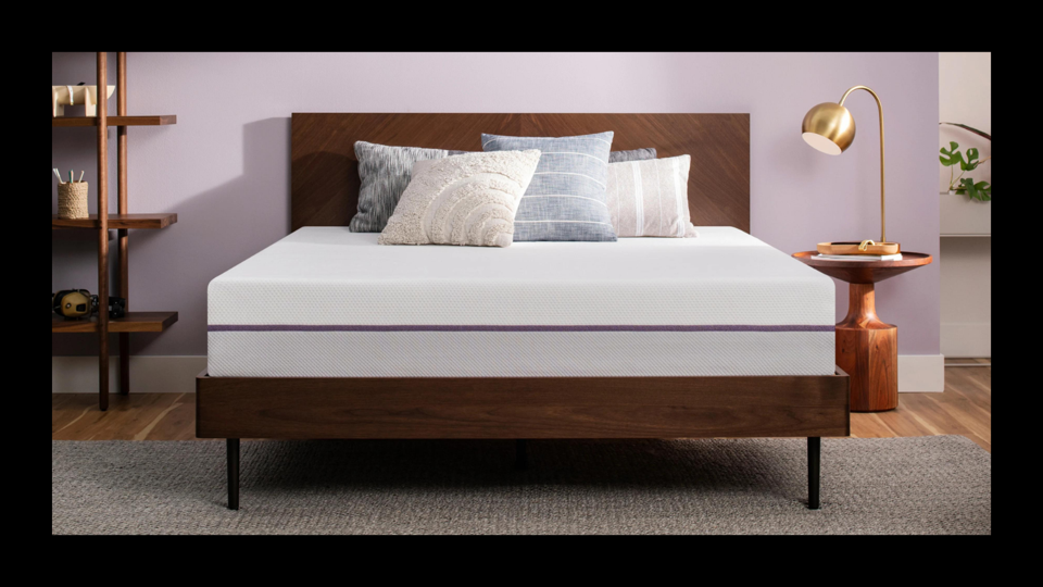 Lifestyle image featuring the Purple mattress on a wood bed frame in a purple bedroom. 