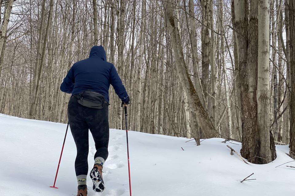 A person walking up a snowy hill with the Black Diamond Pursuit FLZ trekking Poles