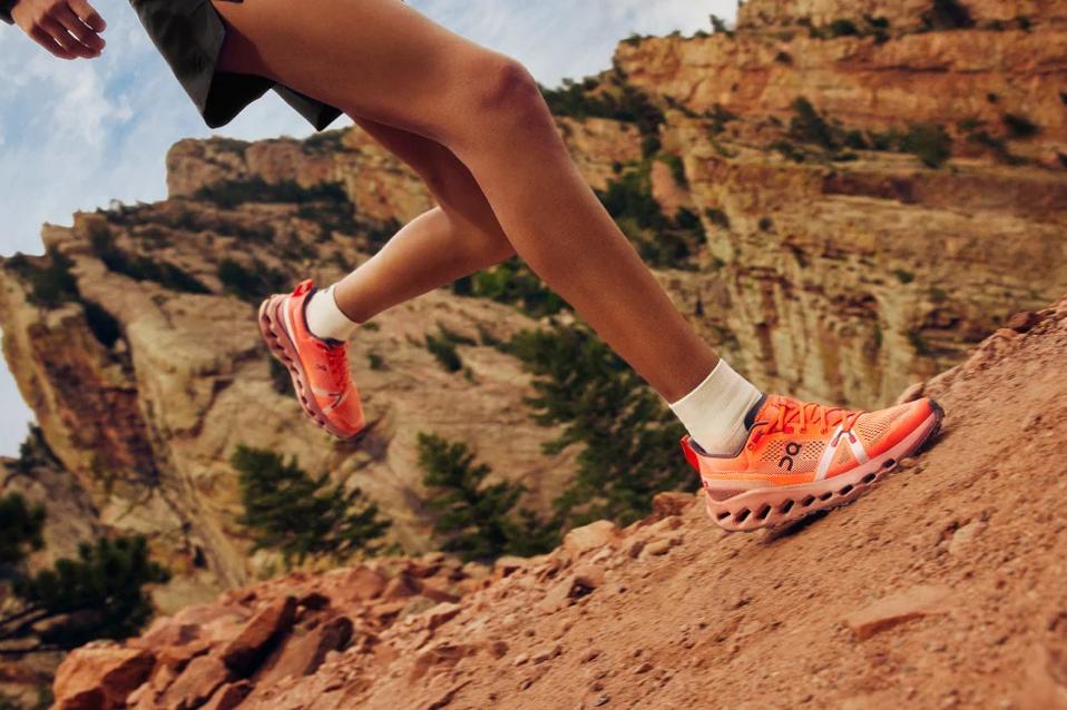 A person running in a pair of orange On Running shoes in the desert