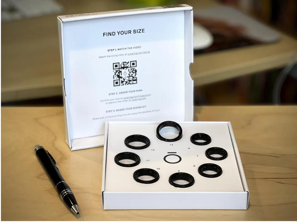 Photo of oura gen3 ring kit white box open on wood table with black pen next to it.