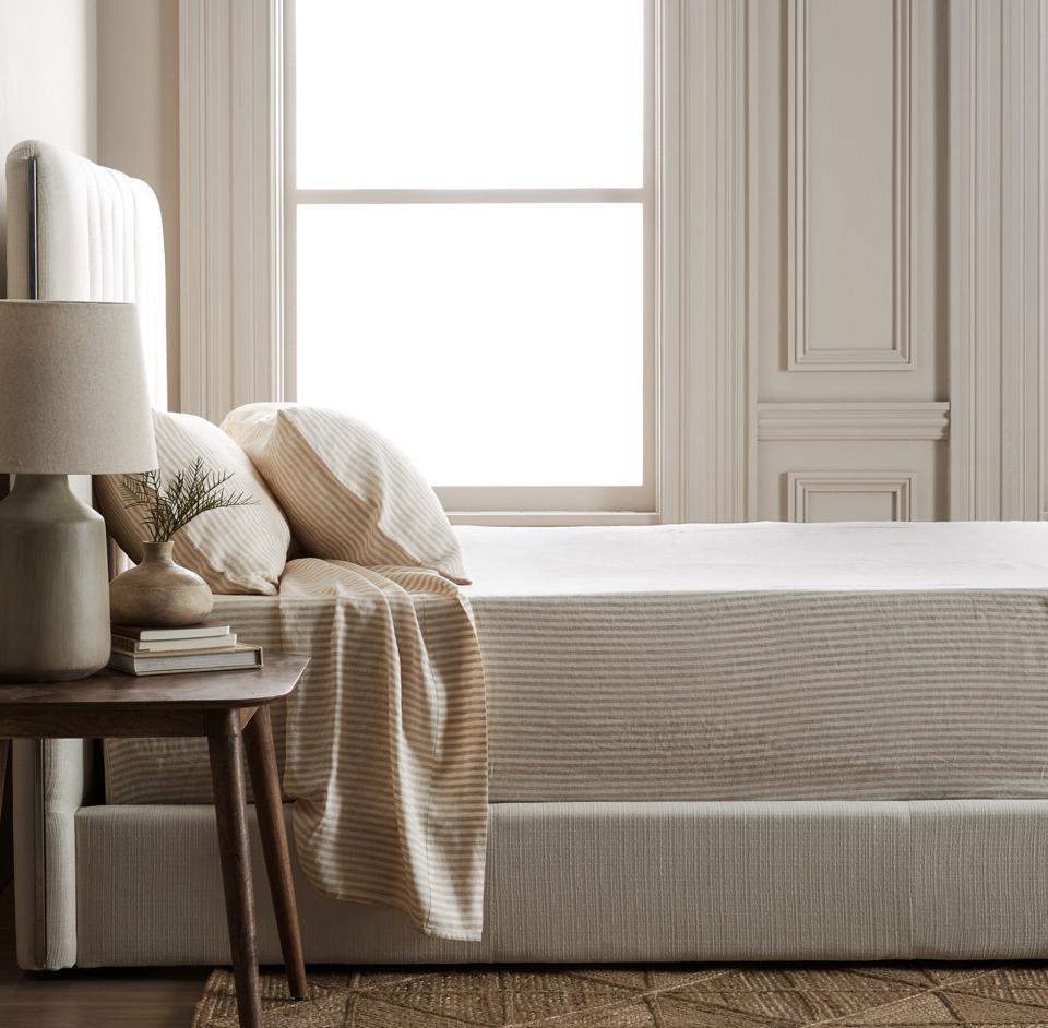 Lifestyle image of bed made with Quince European Linen Sheet Set in Natural/White Stripe.