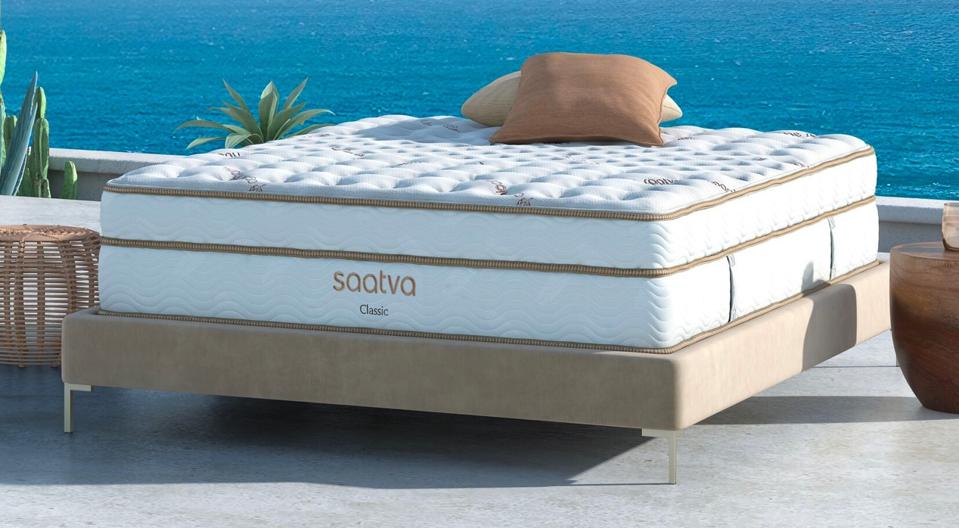 Saatva Classic Mattress on a bed frame in front of a beach. 