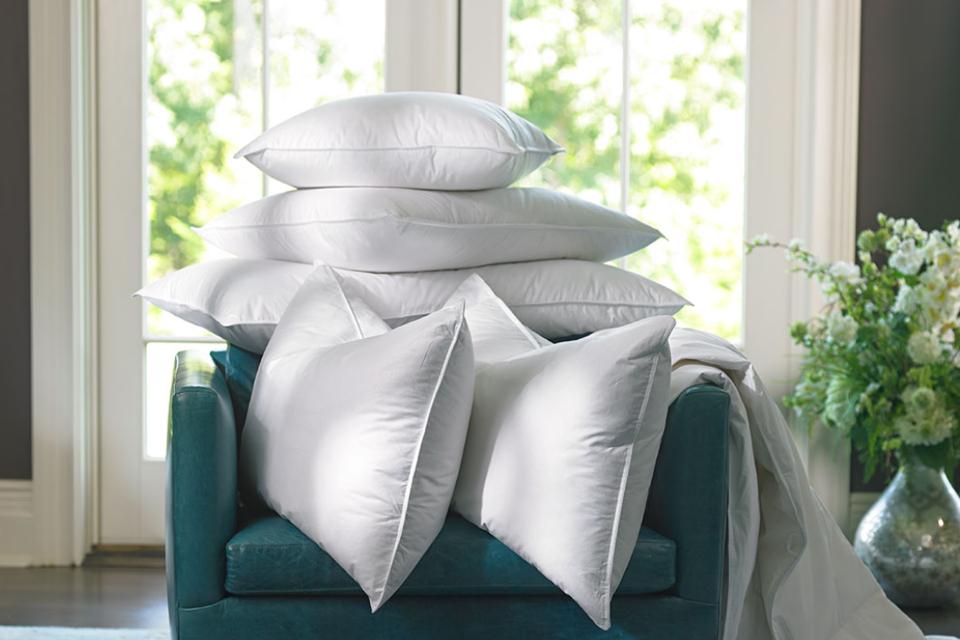 Stacks of The Ritz-Carlton Pillow on a teal armchair in a hotel room