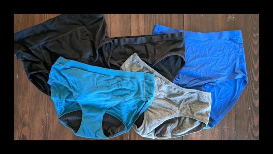 Five pairs of period underwear against a wooden surface