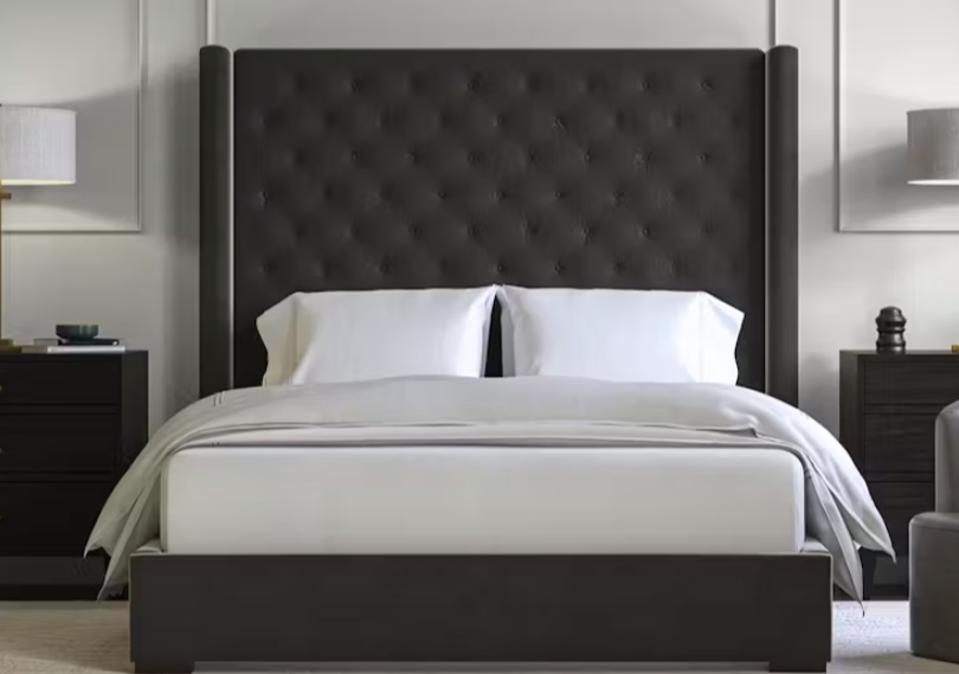 The Saatva Amalfi bed frame with a mattress and pillows on it in a bedroom