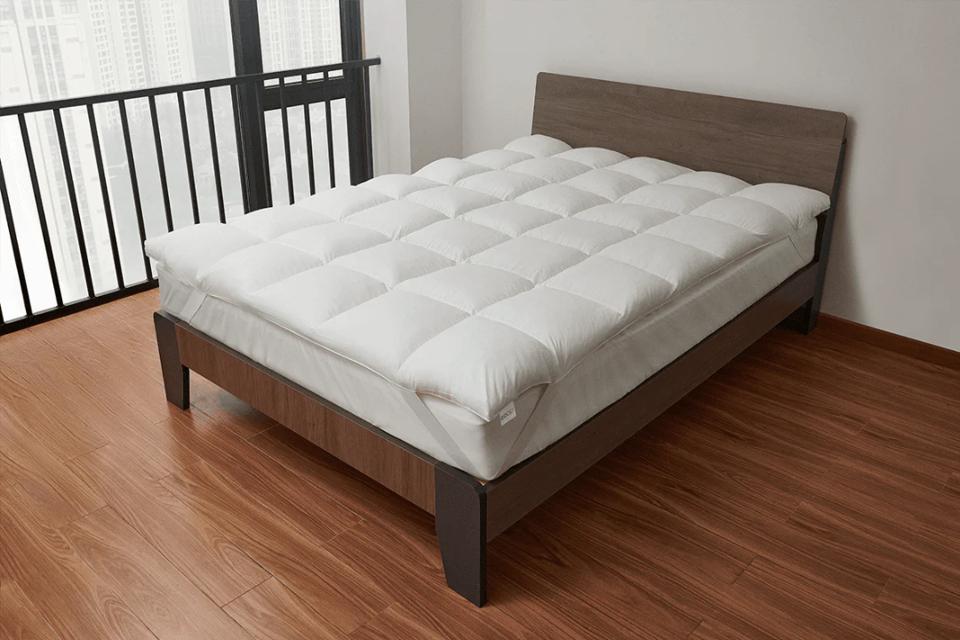 The Coop Sleep Goods Retreat Mattress Topper on a mattress on a bed frame on wood flooring