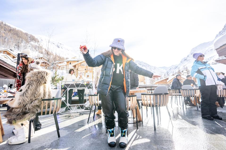 A woman standing on a patio, dancing in a bucket hat and winter attire