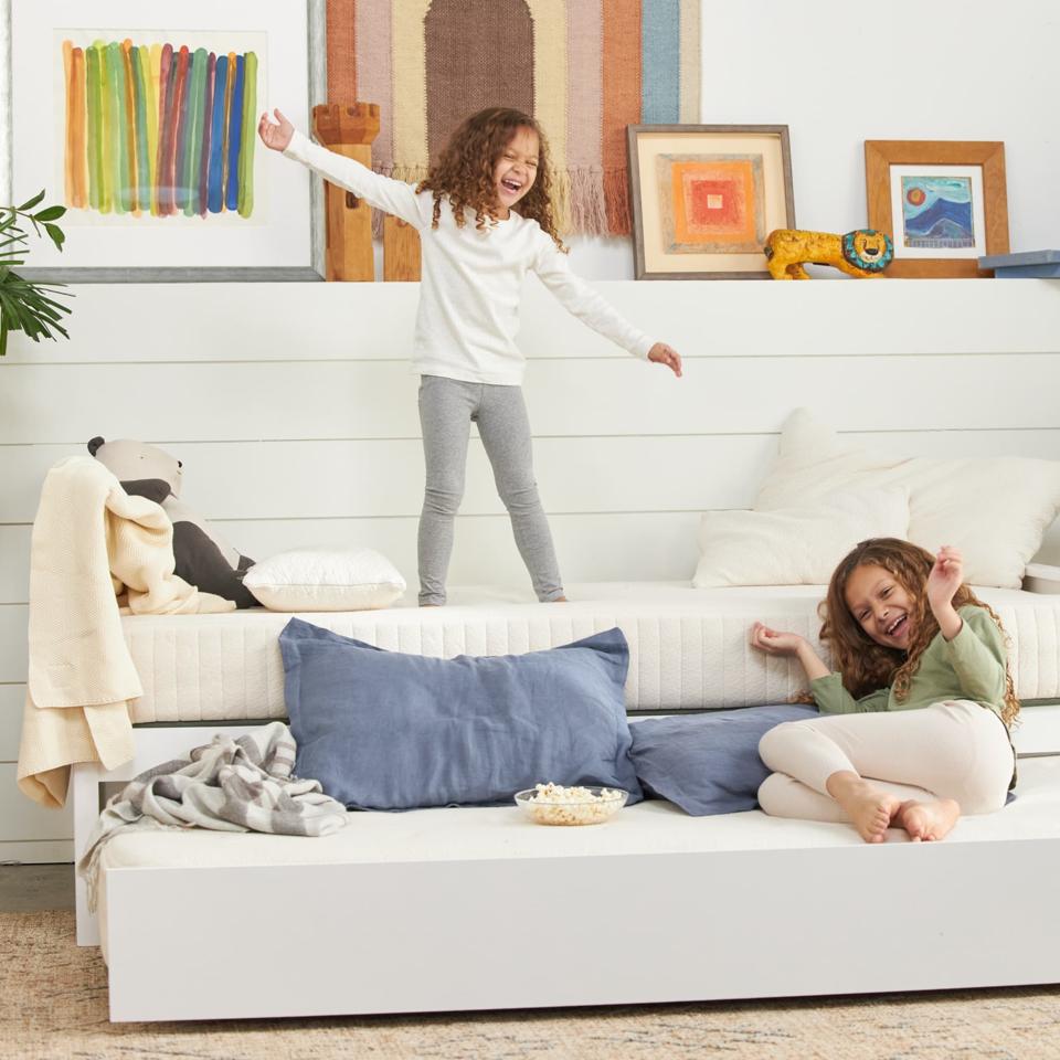 Two girls play on a trundle bed with an Avocado Eco Organic Kids Mattress