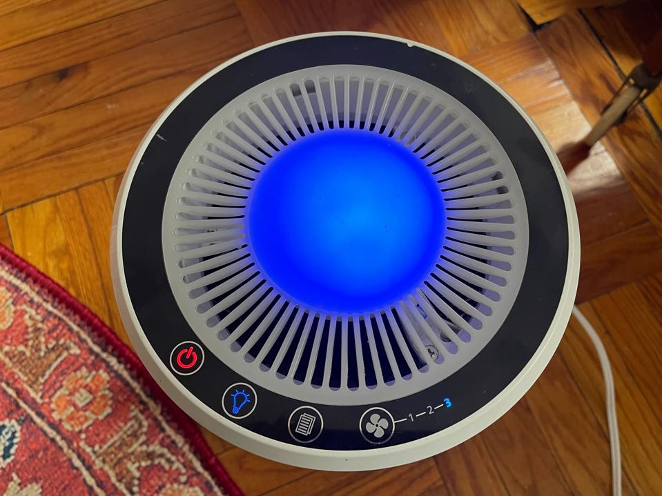 top of Levoit LV-H132 air purifier with power light fan buttons soft blue light on wood floor