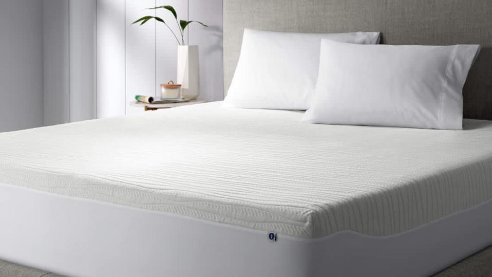 The Sleep Number Total Protection Mattress on a bed with a fabric headboard.