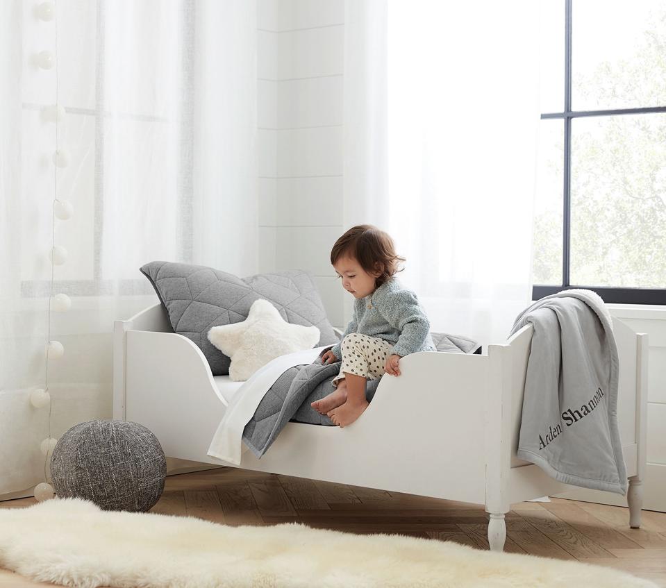 Little girl sitting on Pottery Barn Kids Shelter Bed, next to a star pillow