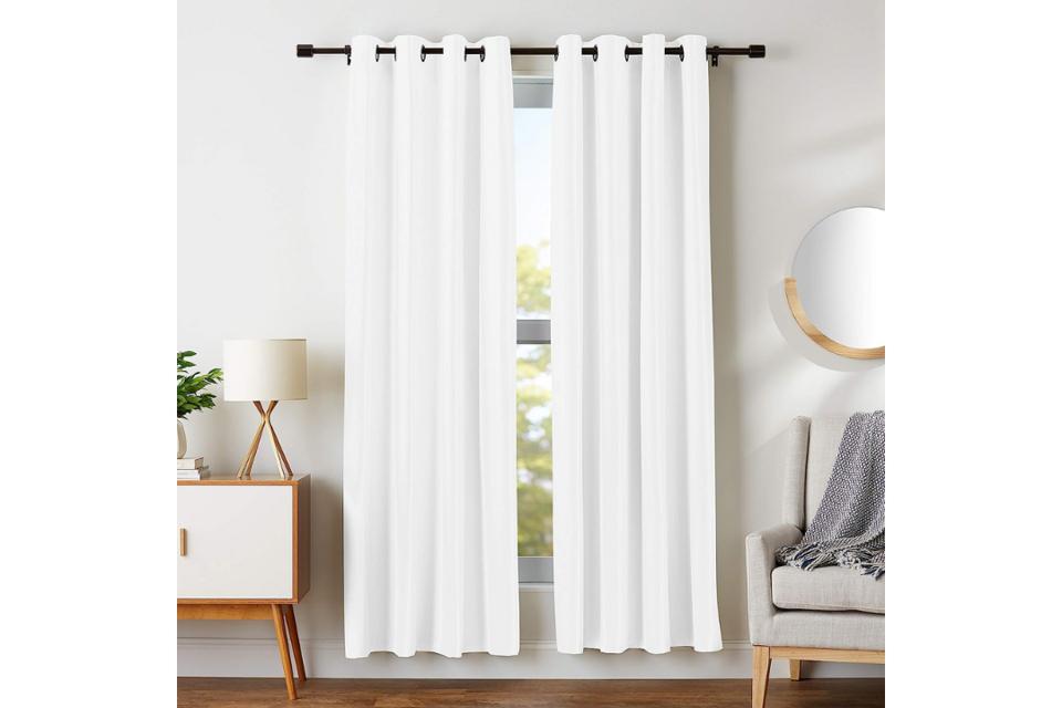 Amazon Basics Room Darkening Blackout Window Curtains in white hanging on a sunny window