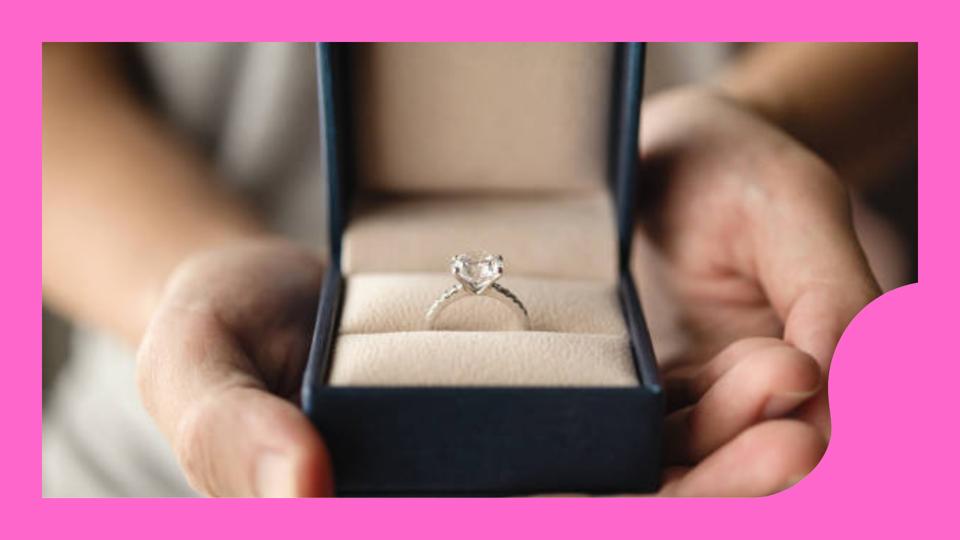 person proposing with diamond engagement ring against pink background