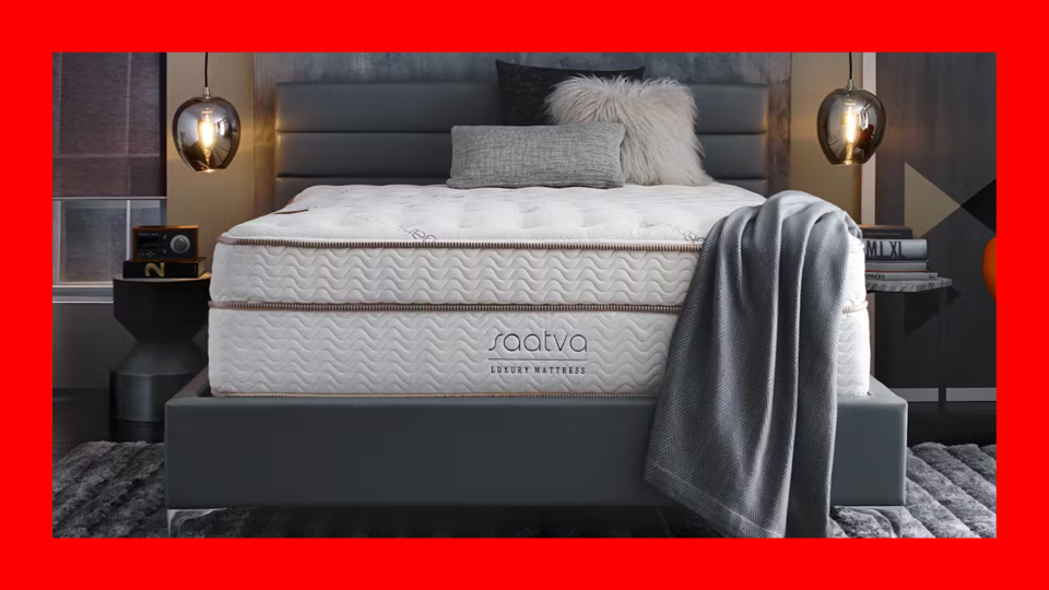 The Saatva Classic Mattress on a bed frame with pillows in a room with a red border