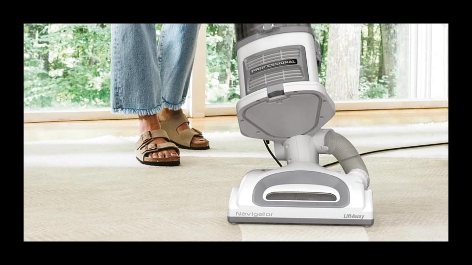 A woman using a Shark vacuum on a carpet 