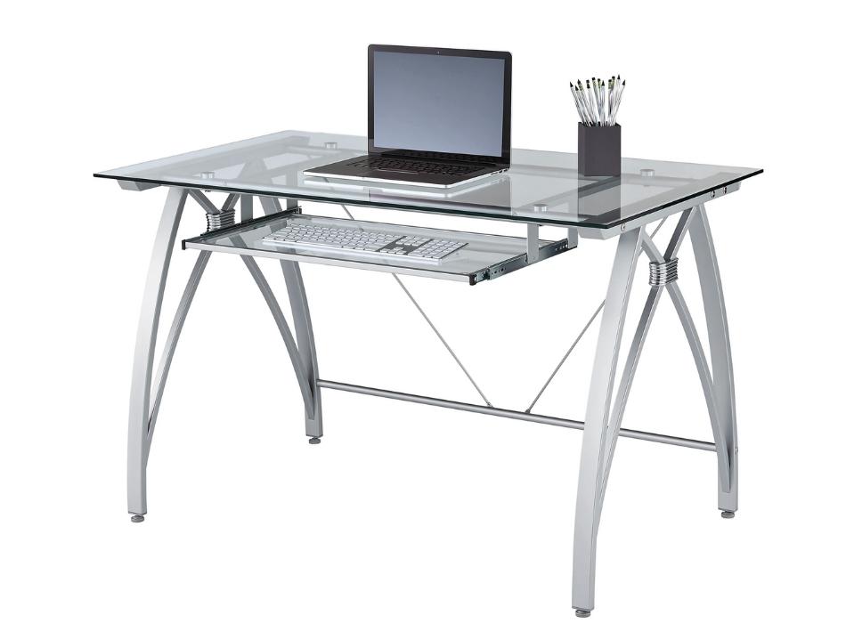 Best Desk: Realspace Vista Glass Computer Desk pictured in a room against a blue wall, with a white upholstered leather chair placed on a blue and white rug. 