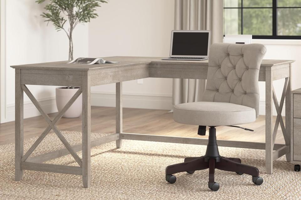 Bush Furniture Key West L-Shaped Desk in an office next to an upholstered desk chair