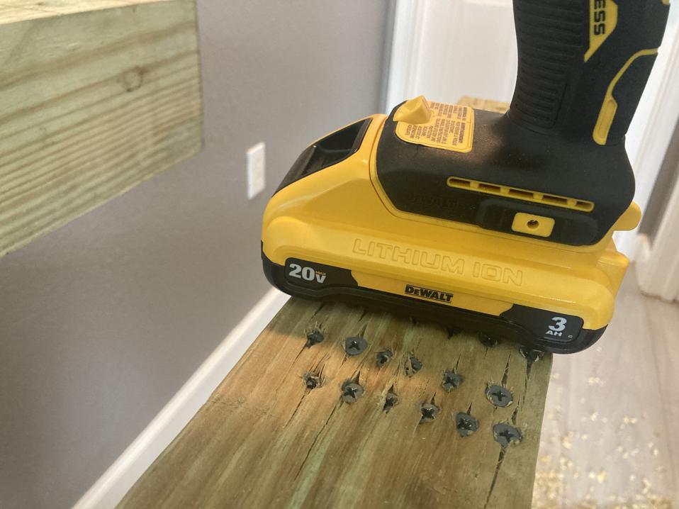 The DeWalt 20V Max Cordless Hammer Drill on top of lumber with several screws drilled in