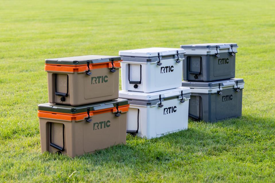 A set of coolers stacked on top of each other in the grass.