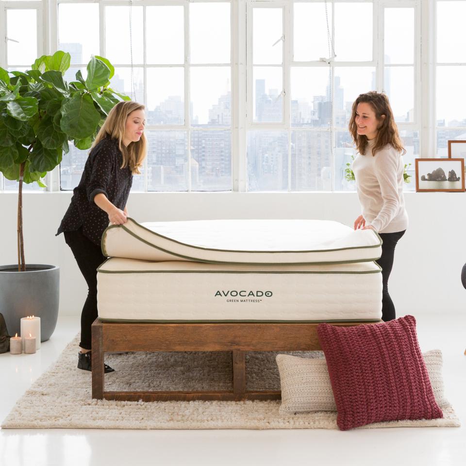 The Avocado Natural Latex Mattress Topper on top of an Avocado mattress and a wooden bed frame. 