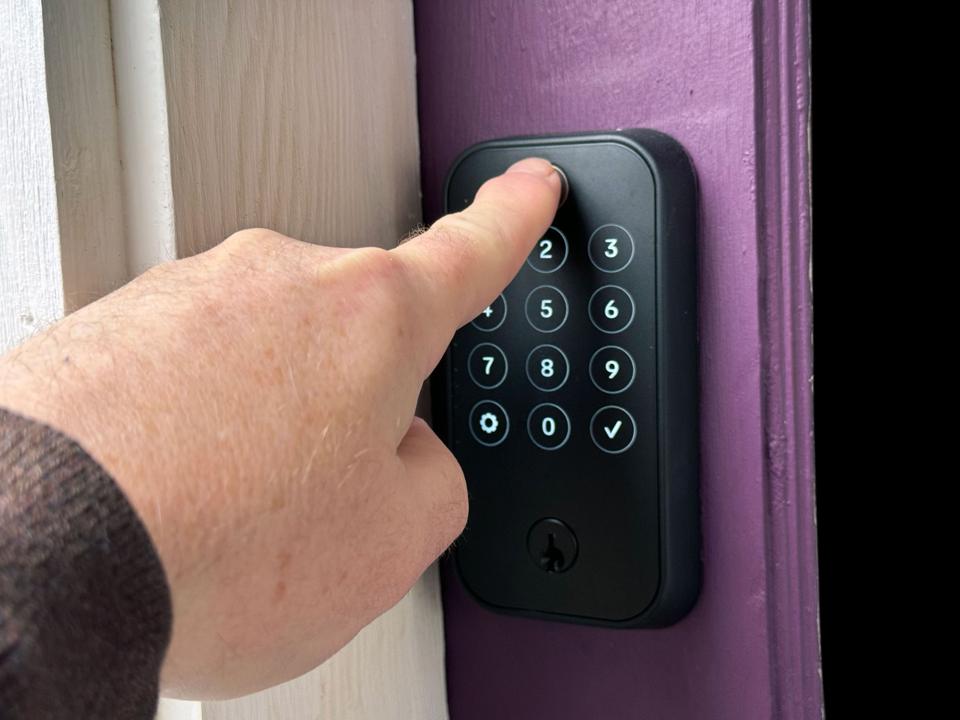 A man pressing his finger on the Yale Assure Lock 2 Touch's fingerprint reader.