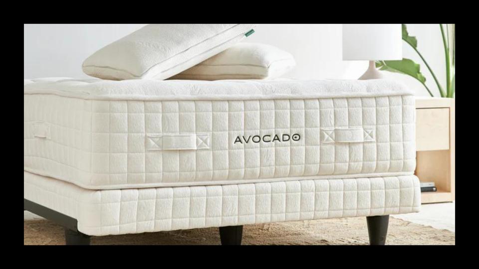 The Avocado Luxury Organic Mattress in a bedroom with pillows on top of it.