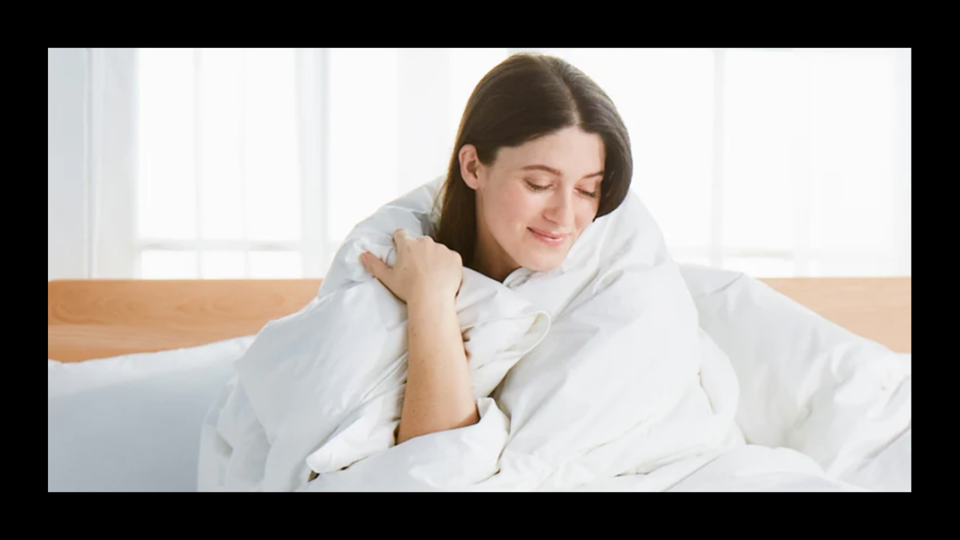 A woman wrapped in an Avocado down comforter