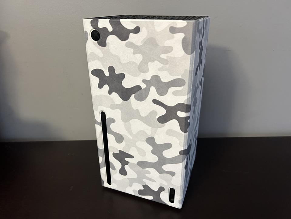 Xbox Series X with a white and gray camouflaged cover design on a tabletop. 